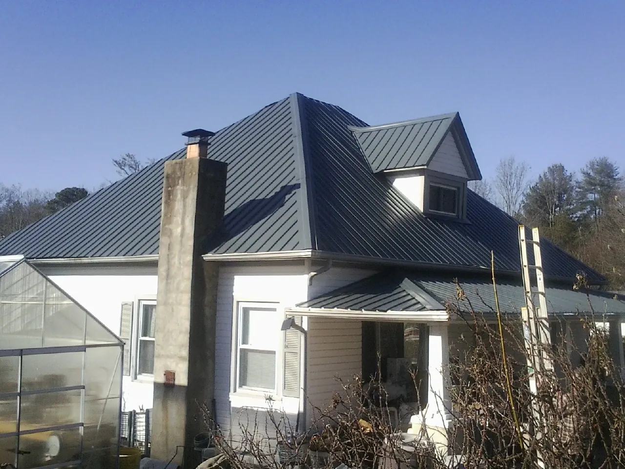Dark blue standing seam metal roof on a white farmhouse with dormer — Slate & Tile Roof Repair by Roofing Brothers in Harriman