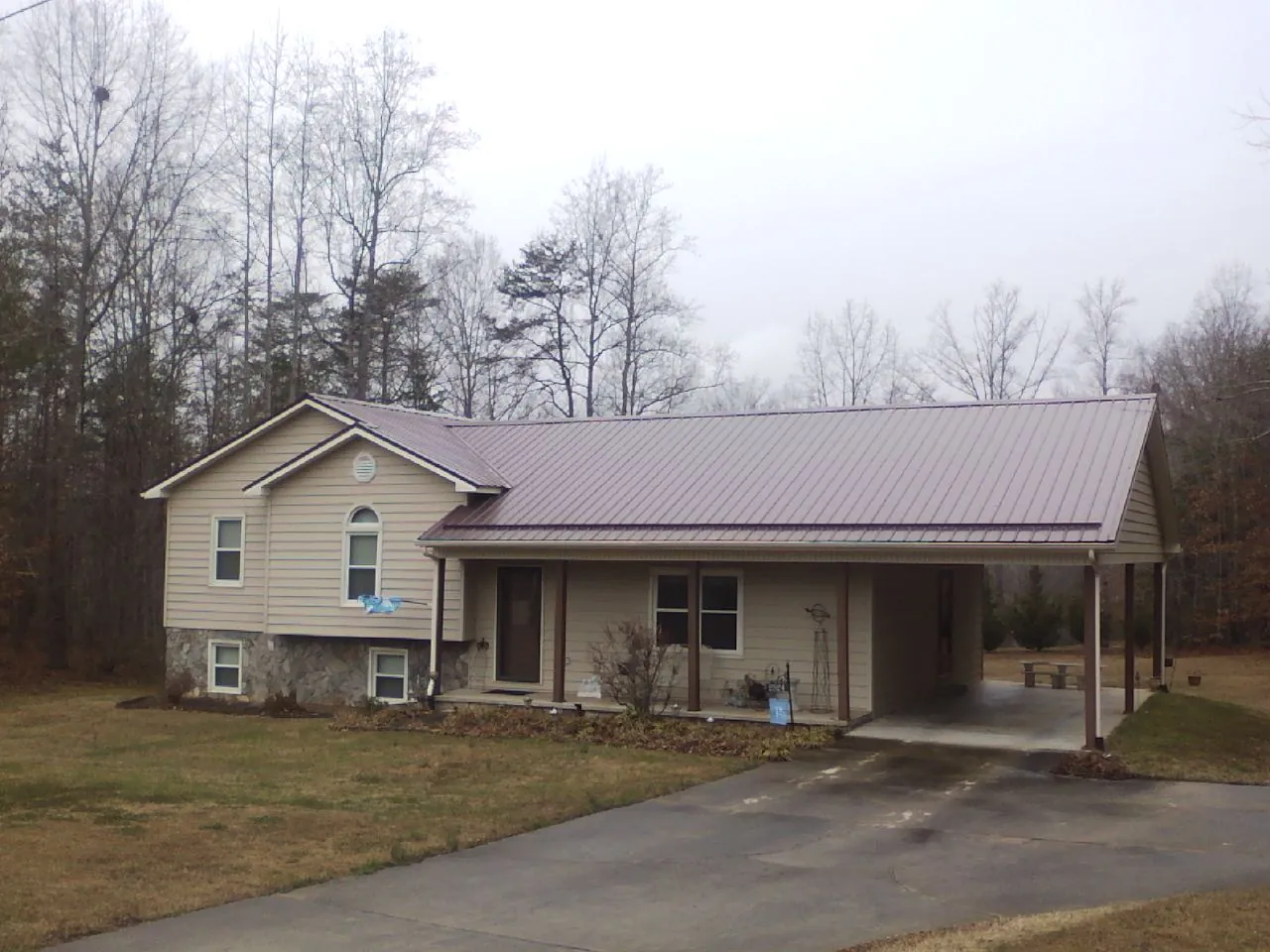 Burgundy metal roof on a tan split level home with an attached carport in Harriman