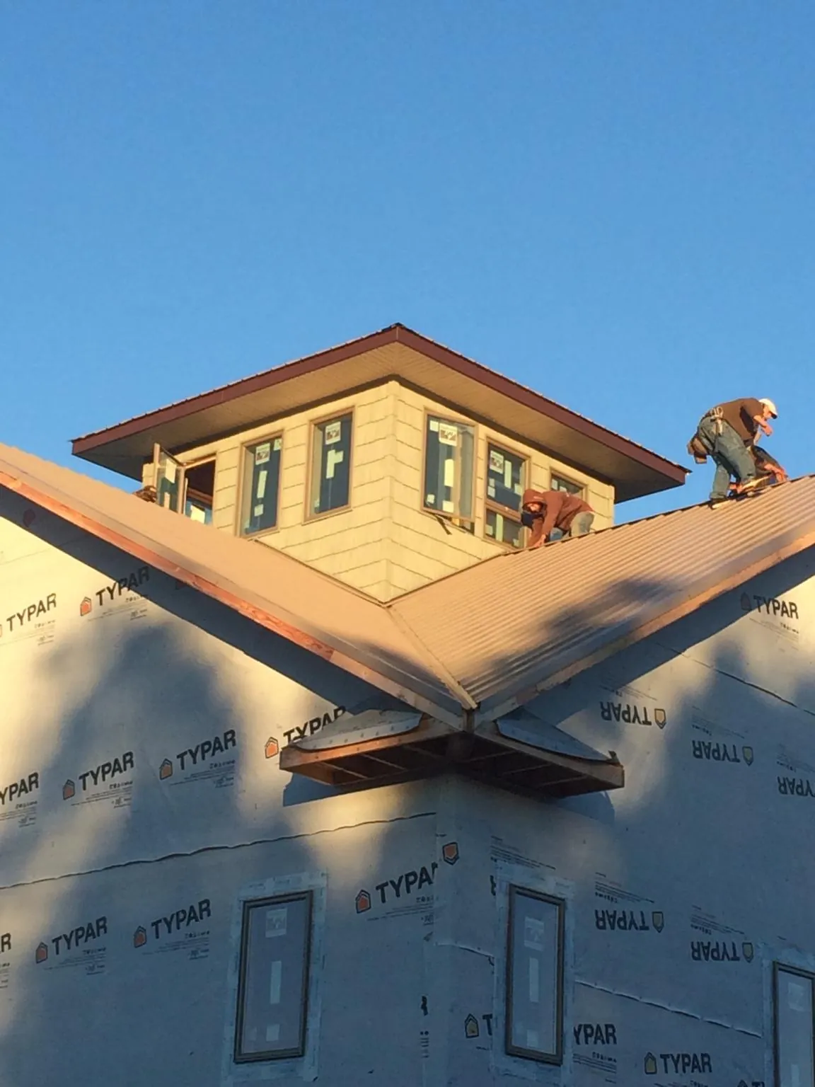 Roofers working around a rooftop cupola on a new metal roof at sunset — Roof Waterproofing in Harriman by Roofing Brothers